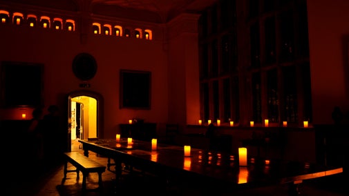 An image of the Great Hall at Trerice in darkness, lit with candles